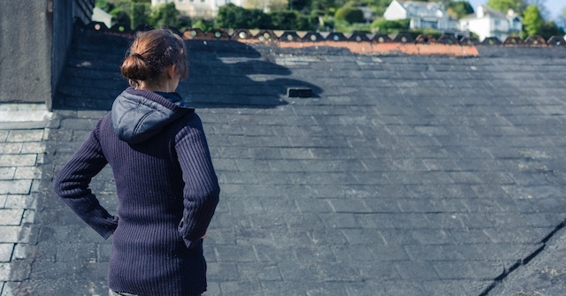 woman checks her roof with checklist signs you need a new roof woman checks her roof with checklist signs you need a new roof